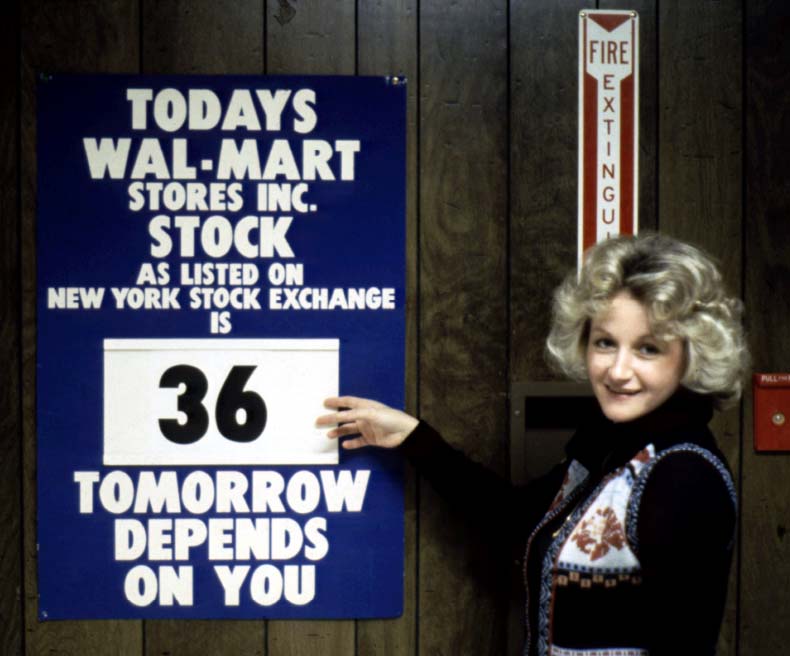 A Walmart associate stands near a New York Stock Exchange sign displayed in the Walmart Home Office.