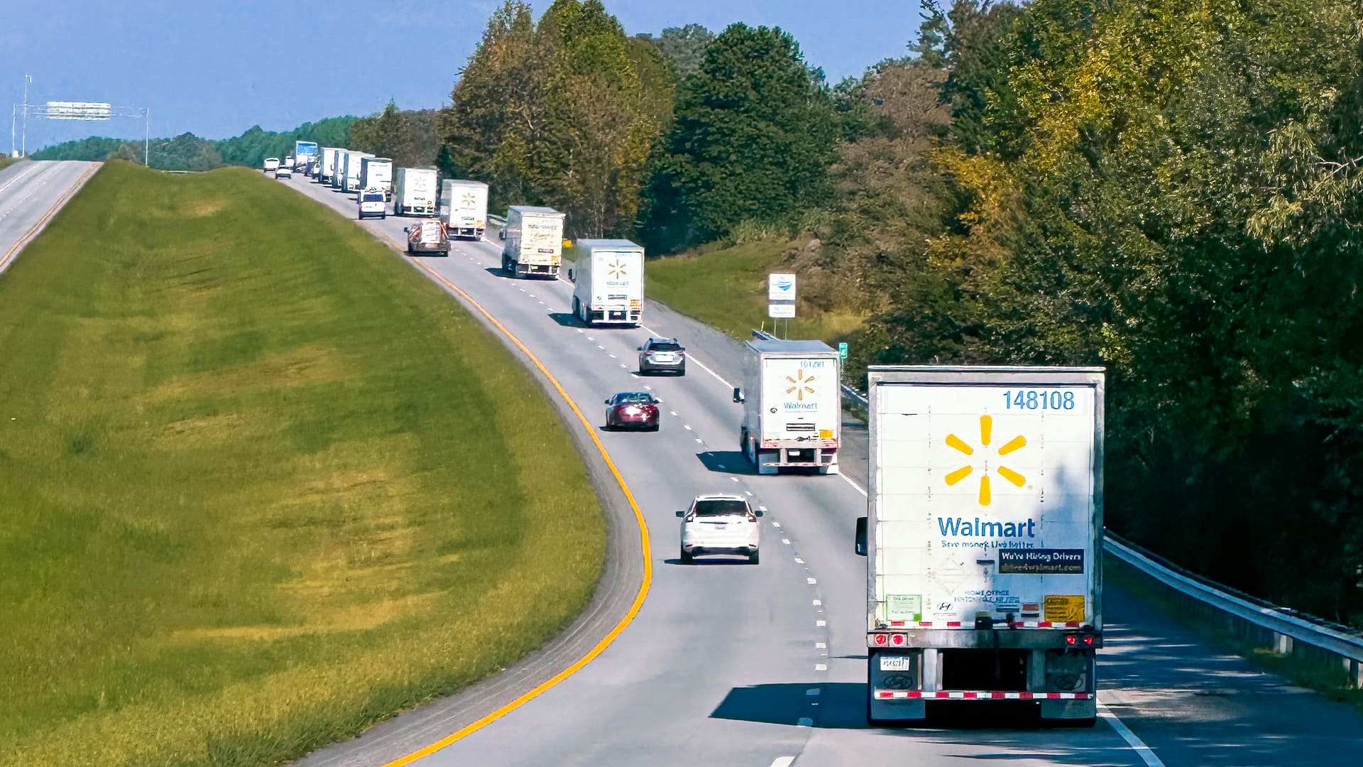 A line of Walmart trucks drive down a road as part of Walmart disaster relief efforts.