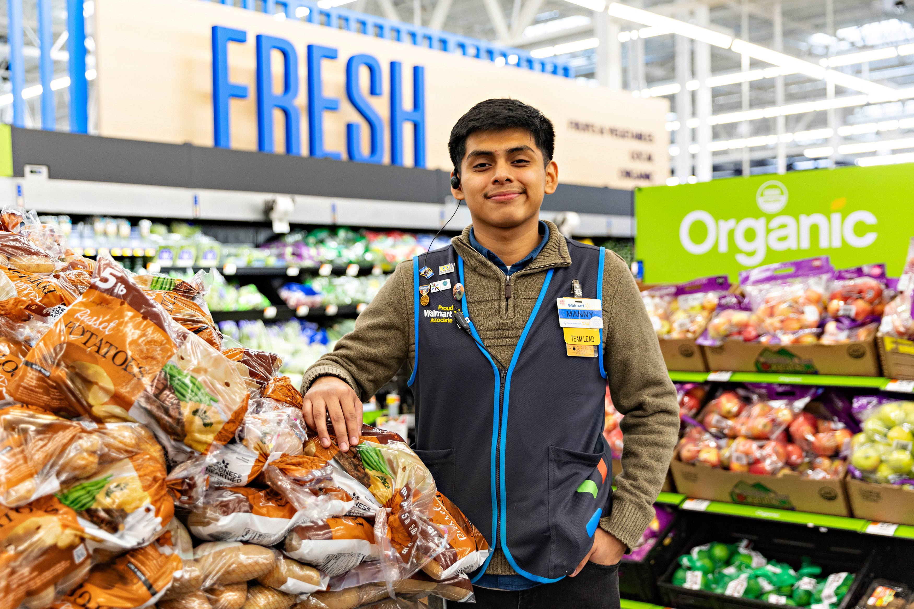 Associate standing next to potatoes in produce area