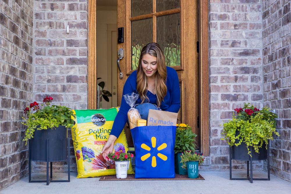 A customer retrieves a Walmart order from her doorstep. Items include potting mix, flowers, bread and a prescription.