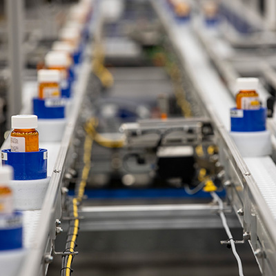 Prescription bottles on a conveyor belt in a Walmart Pharmacy Central Fill facility.