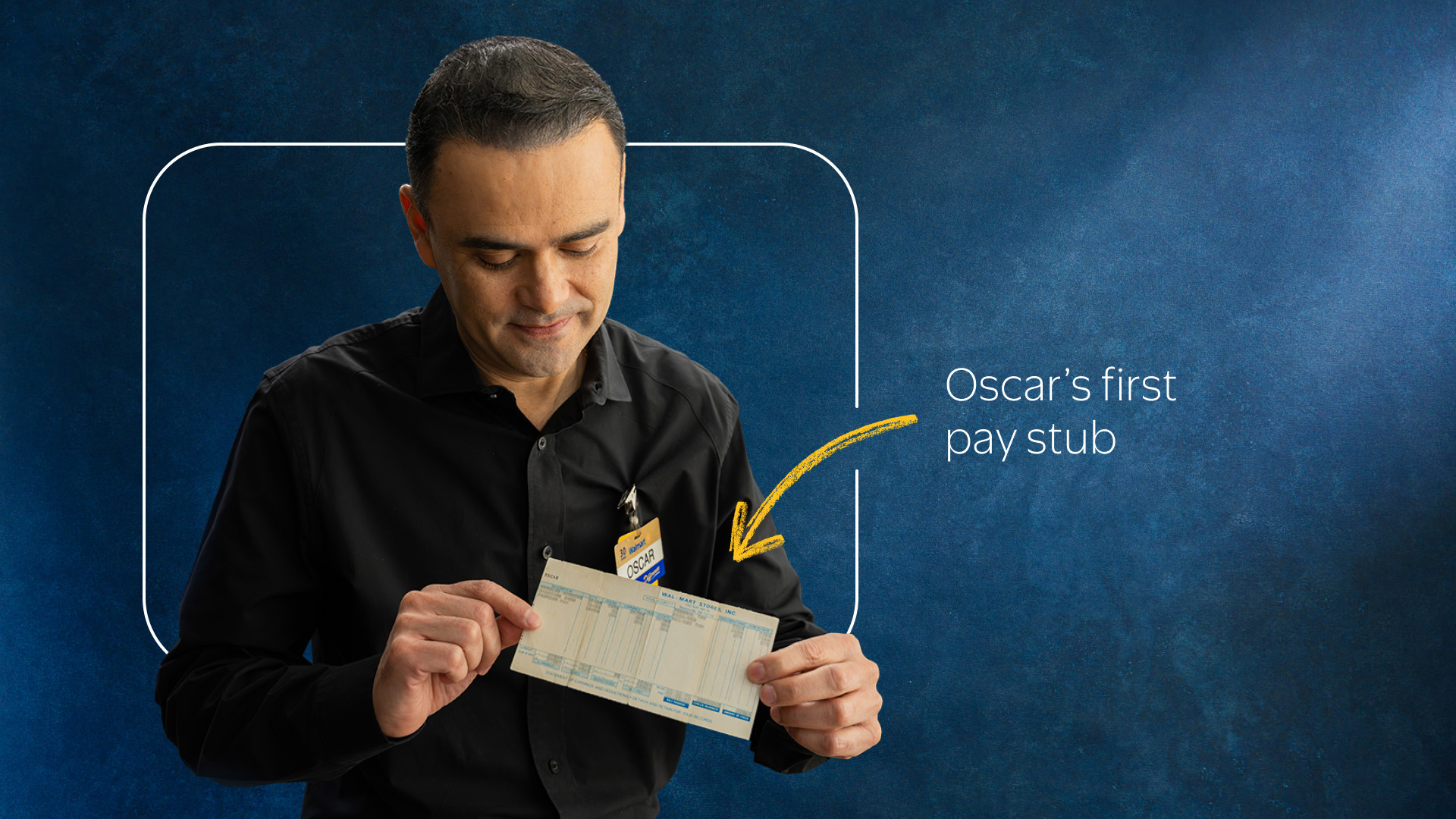 Oscar Romero holding his first Walmart pay stub against blue backdrop..