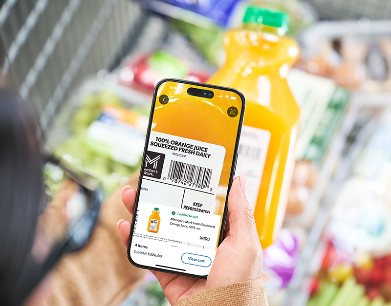 A Sam's Club member scans orange juice with a mobile phone.