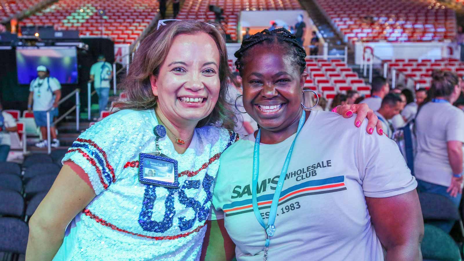 Two Sam's Club associates smile inside Bud Walton Arena in Fayetteville, Ark.