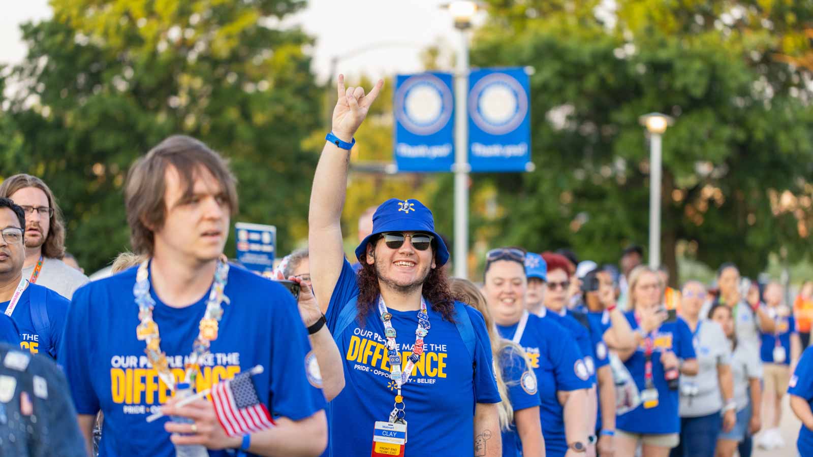 Walmart associate gives the "Rock on" hand gesture to the camera while standing in line during an Associate's Week celebration.