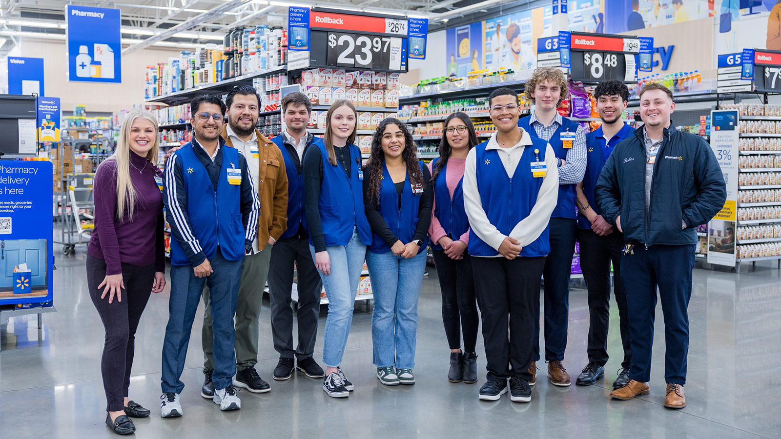 A group of Walmart associates standing in a Walmart store in front of a grocery aisle