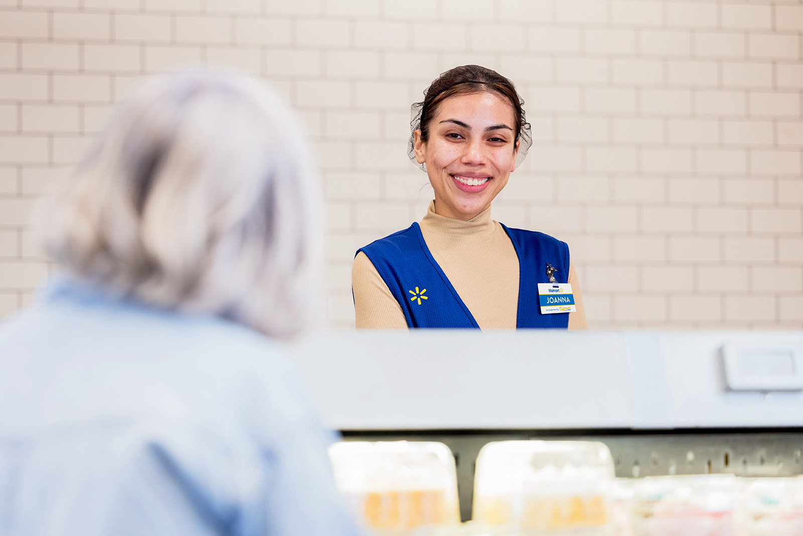 Walmart Associate smiling behind a deli counter.