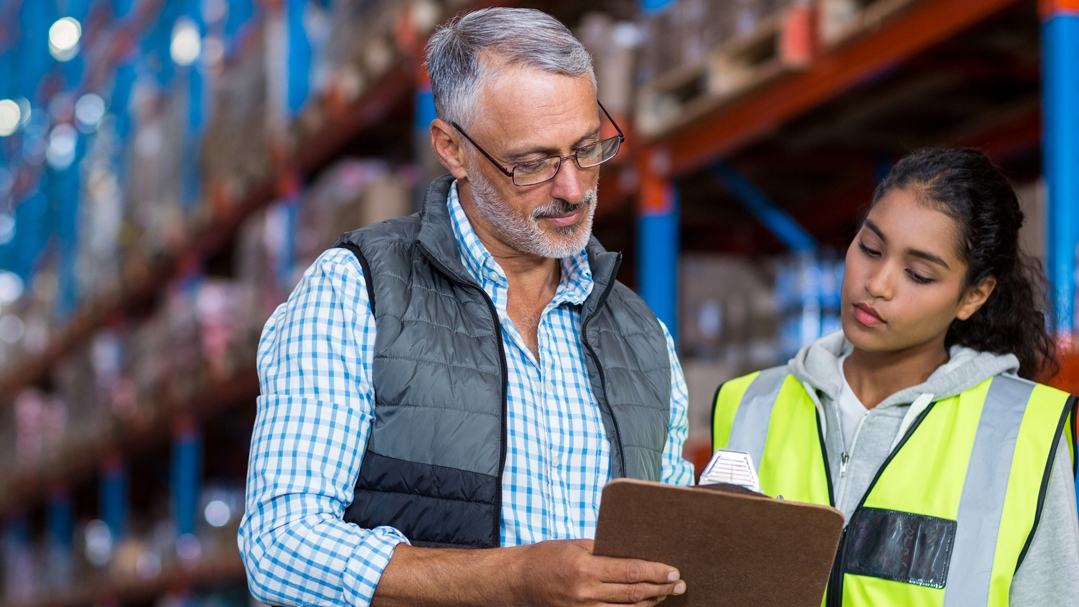 Two people review a clipboard in a warehouse