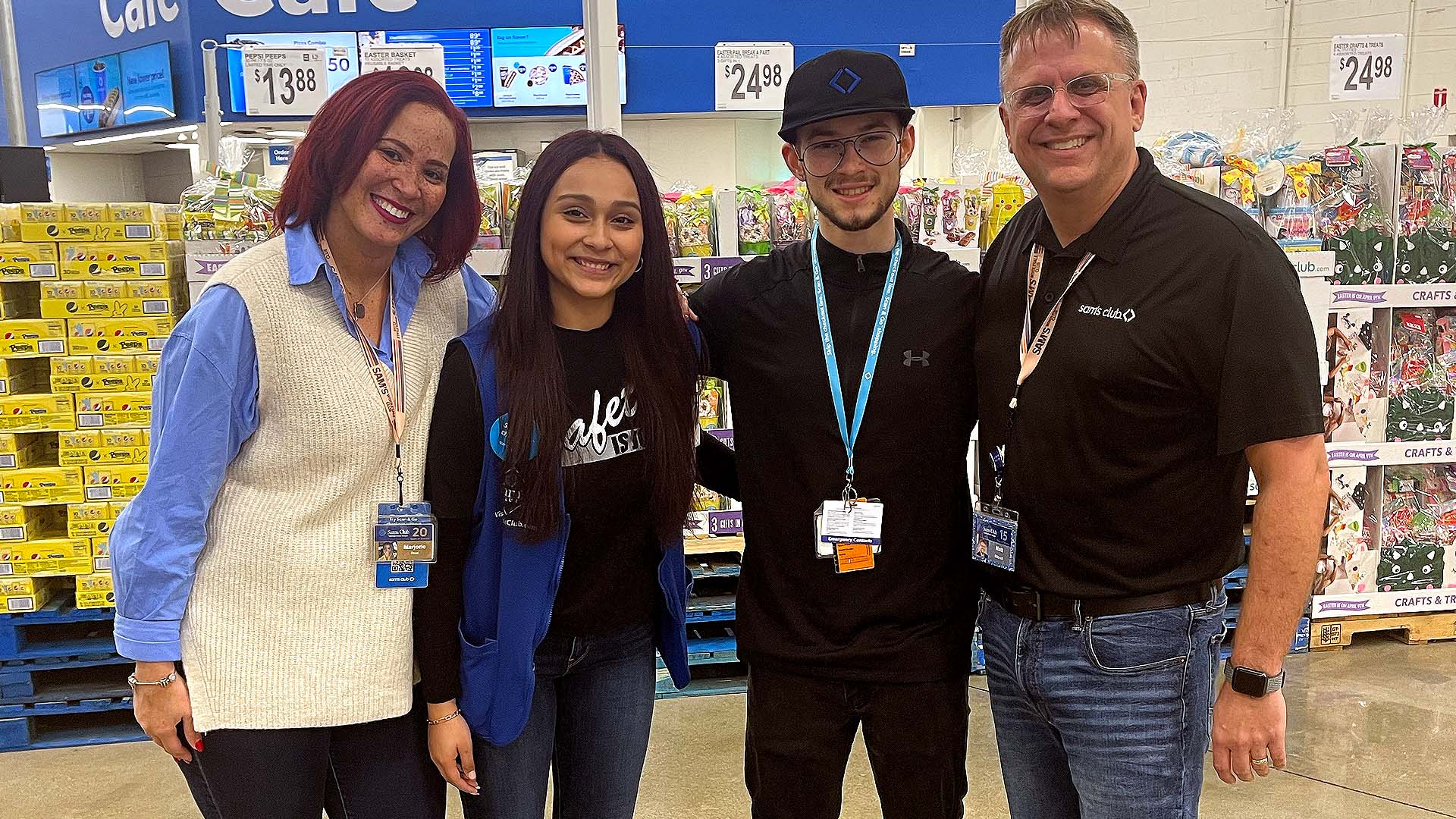 A smiling quartet: two Sam’s Club high school interns stand in a club aisle with two Sam’s Club team members and smile for a photo.