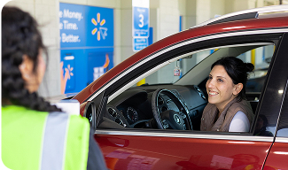 A photo of a customer interacting with a Walmart associate in a car order pickup location.