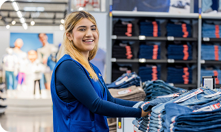 Photo of a Walmart associate working in an apparel department and smiling at the camera.